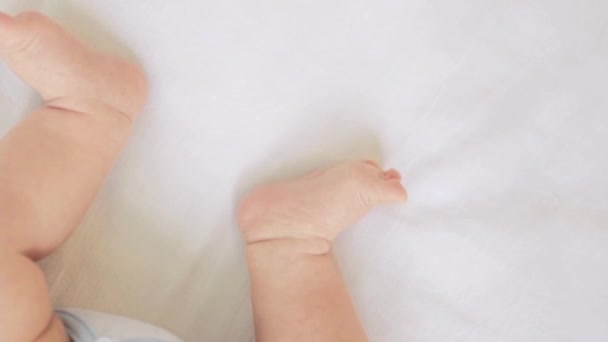 Nogi noworodka z obcasami na bawełnianym łóżku w domu — Wideo stockowe