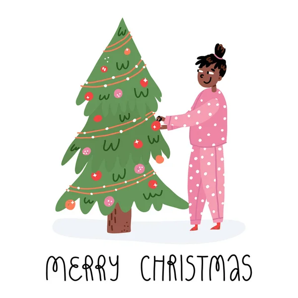 Ragazza afroamericana in pigiama accogliente decorare l'albero di Natale con le bagattelle. Buon Natale biglietto con scritte a mano. — Vettoriale Stock