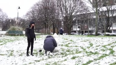 Londra, İngiltere. 24 Ocak 2021. Londra 'daki ilk kar yağışında insanlar kardan adam yapmak için yuvarlanıyor. Covid-19 kar yağışı sırasında neşeli ruh hali.
