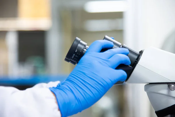 Κοντινό Πλάνο Επιστήμονας Χέρι Μπλε Γάντι Χρησιμοποιώντας Μικροσκόπιο Στο Εργαστήριο — Φωτογραφία Αρχείου