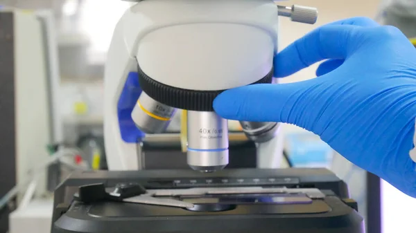 Χέρι Επιστήμονας Μπλε Γάντι Χρησιμοποιώντας Μικροσκόπιο Στο Εργαστήριο — Φωτογραφία Αρχείου