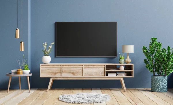 Mockup television on cabinet in contemporary empty room with dark blue wall behind it.3D rendering