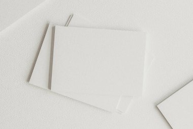 Kağıt üzerine yerleştirilmiş beyaz boş kartların üst görünümü. Minimalist kompozisyon ve yumuşak ışıklandırma temiz tasarımı vurguluyor - 3D canlandırma