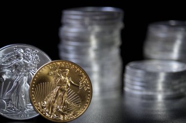 Odak noktası altın ve gümüş Amerikan kartalı parası. Arka planda gümüş kartal paraları var.