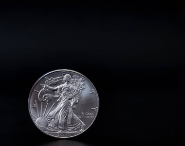 Bir onsluk Amerikan gümüş kartalı sikkesi siyah arka planda dikey duruyor, fotokopi uzayı var.