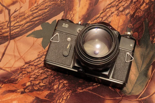 Photo of retro camera on the camouflage — Stock Photo, Image