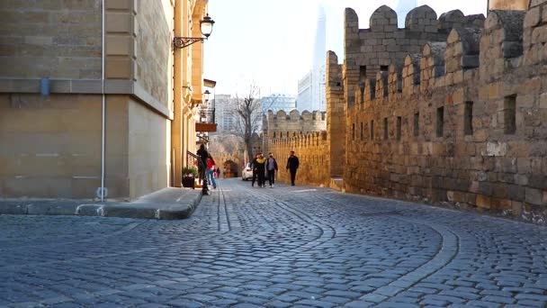 Ommuurde oude stad van Bakoe - Azerbeidzjan. Voorjaar 2021. Mensen lopen in de kasseistraat van de oude stad - Icherisheher. — Stockvideo