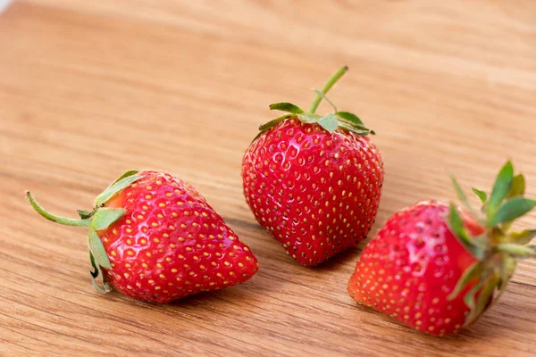 Fragola. Fresco crudo tre bacche su sfondo di legno. — Foto Stock