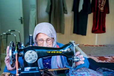 Arap Müslüman kadın eski dikiş makinesi kullanıyor.