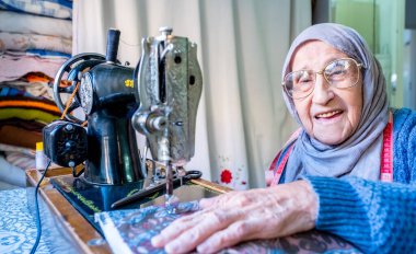 Arap Müslüman kadın eski dikiş makinesi kullanıyor.