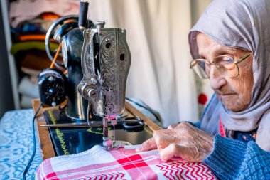 Arap Müslüman kadın eski dikiş makinesi kullanıyor.