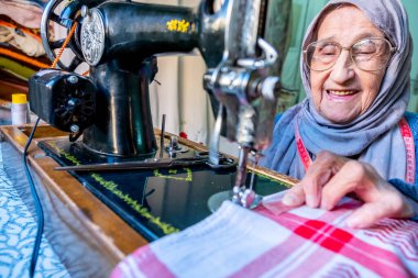 Arap Müslüman kadın eski dikiş makinesi kullanıyor.