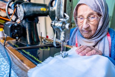 Arap Müslüman kadın eski dikiş makinesi kullanıyor.
