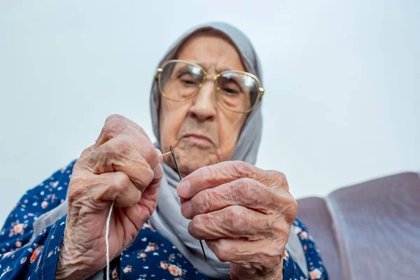阿拉伯穆斯林老妇人把线插在针头上 — 图库照片