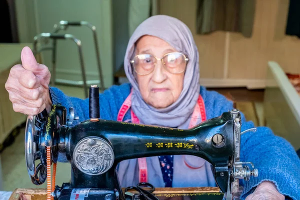 用缝纫机缝制的阿拉伯穆斯林老太太开心极了 — 图库照片