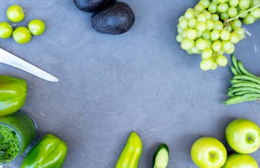 Gri arka planda meyveler ve sebzeler bir çerçeve oluşturur