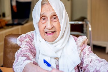 Yaşlı kadın portresi tablet ve defter kullanarak okuyor, yazıyor ve öğreniyor.