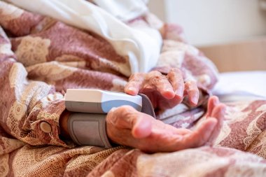 Arap yaşlı kadın elektronik basınç cihazı kullanarak tansiyonunu ölçüyor.