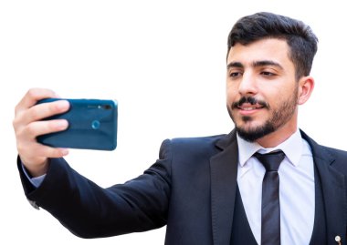 Takım elbiseli ve cep telefonuyla selfie çeken bir adam gülümseyerek ve teçhizatlı.