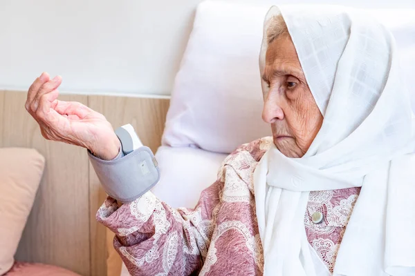 Arabic old woman check her blood pressure using electronic pressure device