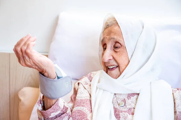 アラビア語の老婦人は彼女の血圧をチェックします電子圧力デバイスを使用して — ストック写真