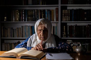 Yaşlı kadın sabah vakti kitap yazıyor ve okuyor.