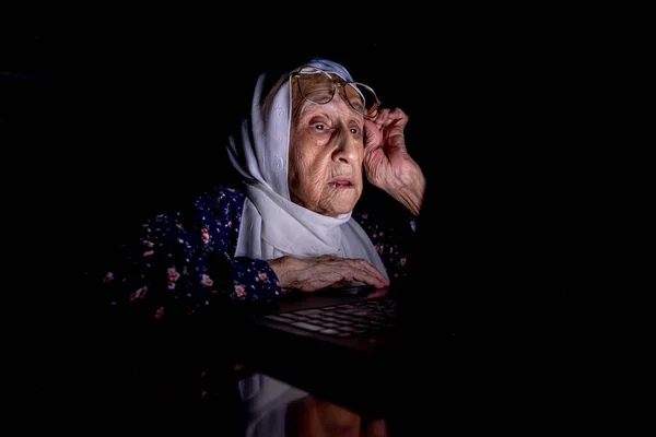 老太太半夜在黑暗的房间里工作在笔记本电脑上 — 图库照片