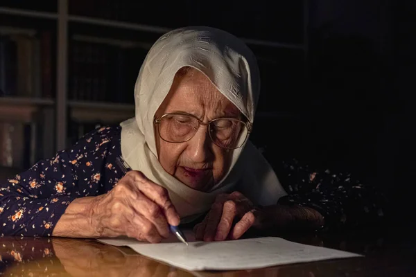Old lady reading books in dark room with candles light and writing down some notes