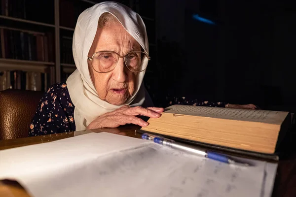 Old lady reading books in dark room with candles light and writing down some notes