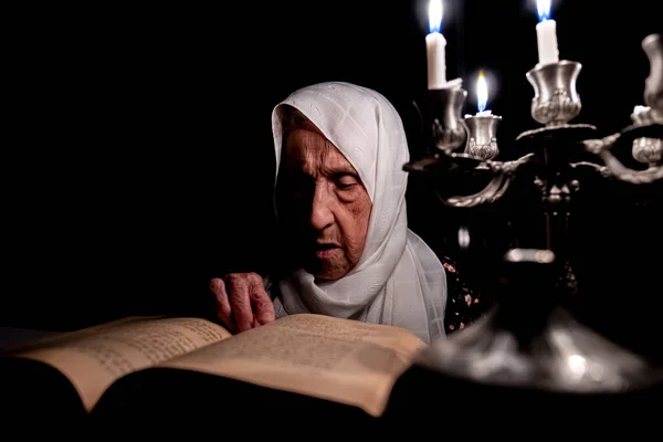 Old woman reading books in dark room with candles light