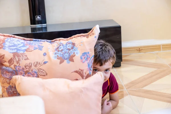 Arabic boy playing hide and seek and hiding behind cushion