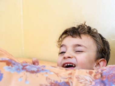 Arap çocuk saklambaç oynuyor ve yastıkların arkasına saklanıyor.