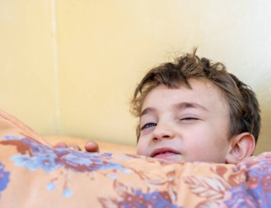 Arap çocuk saklambaç oynuyor ve yastıkların arkasına saklanıyor.