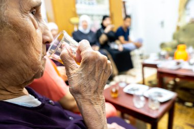 Yaşlı Müslüman kadın dinlenmek için çay içiyor.