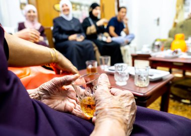 Yaşlı Müslüman kadın dinlenmek için çay içiyor.
