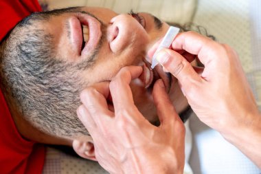 Doktor hastasına göz damlası veriyor.