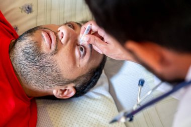 Doktor hastasına göz damlası veriyor.