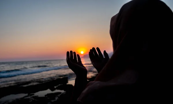 Kadınlar gün batımında sahilde Allah 'a dua ediyorlar.