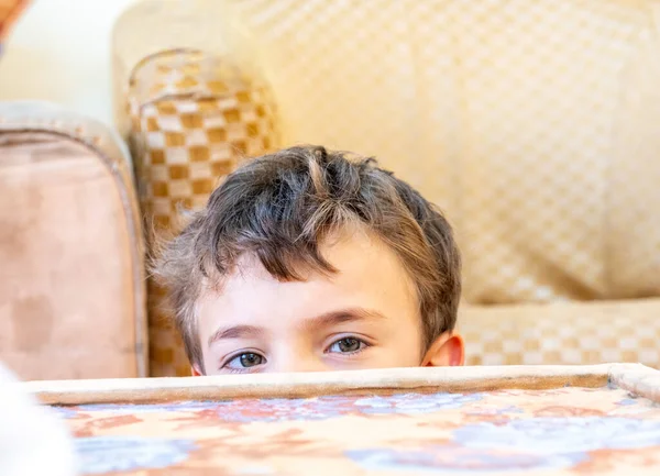 Arabic boy playing hide and seek and hiding behind cushion
