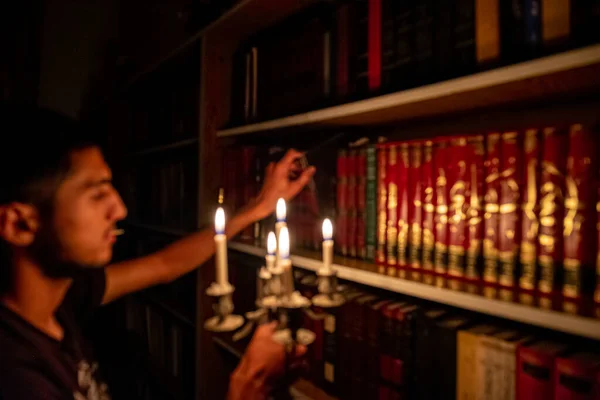 Boy holding book from the library in the dark with candles to light his way