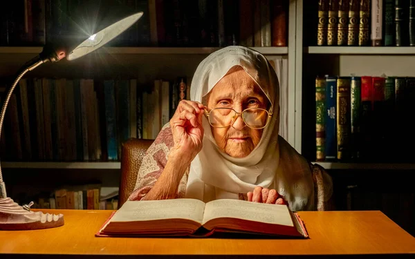 Arabic muslim old woman reading books at night with table lamp light