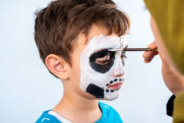 Muslim girl drawing face for young kid look like skull