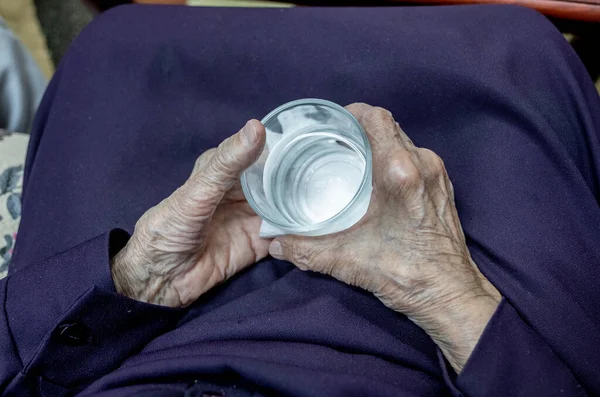 一个老太婆拿着一大杯水喝 — 图库照片