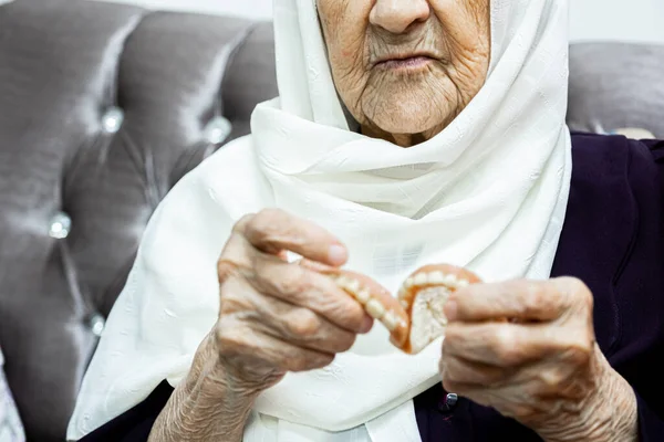 Old muslim woman removing her teethj set