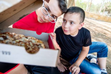 Mutlu Arap oğlanlar parkta pizzanın tadını çıkarıyorlar.