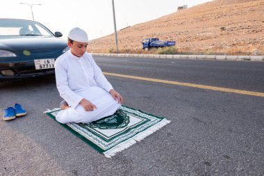Arap çocuk sokakta Tanrı 'ya dua ediyor.