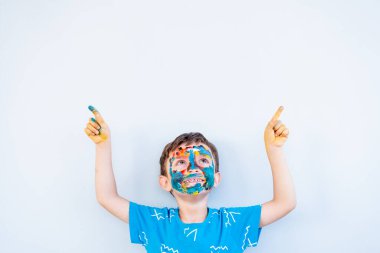 Çocuk ellerini ve yüzünü kullanarak renklerle oynuyor.