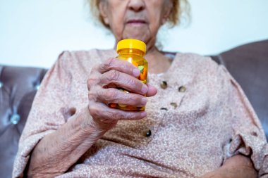 Yaşlı kadın ilaçlarını elinde tutuyor.