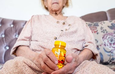 Yaşlı kadın ilaçlarını elinde tutuyor.