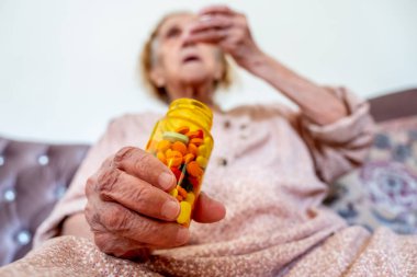 Yaşlı kadın ilaçlarını elinde tutuyor.